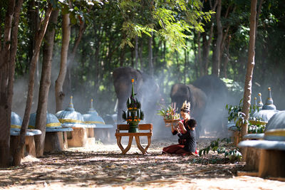 Woman and girl praying while sitting on land