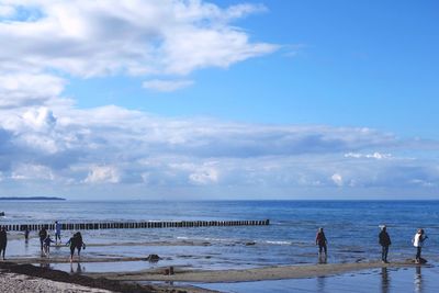 People at beach against sky