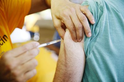 Cropped hands of doctor injecting to patient at hospital