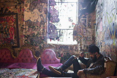 Full length of man sitting on sofa at home