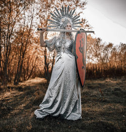 Portrait of woman standing on field in forest