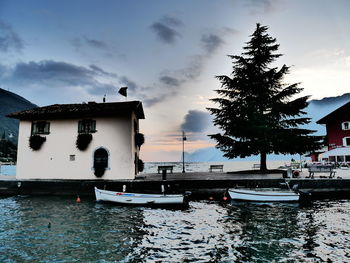 Boats moored on sea by buildings against sky