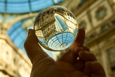 Cropped hand holding crystal ball against monument ceiling 