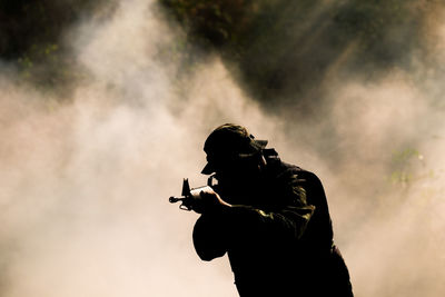 Silhouette soldier against smoke outdoors
