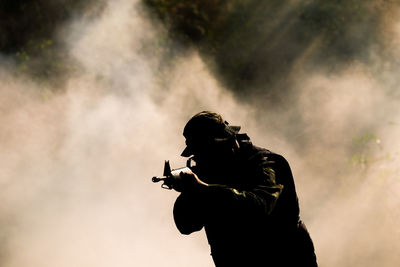 Side view of silhouette man holding umbrella