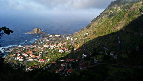 High angle view of town by sea against sky