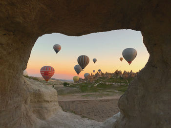 Hot air balloon flying over rock formation against sky