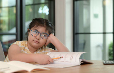 Young woman reading book while sitting at home