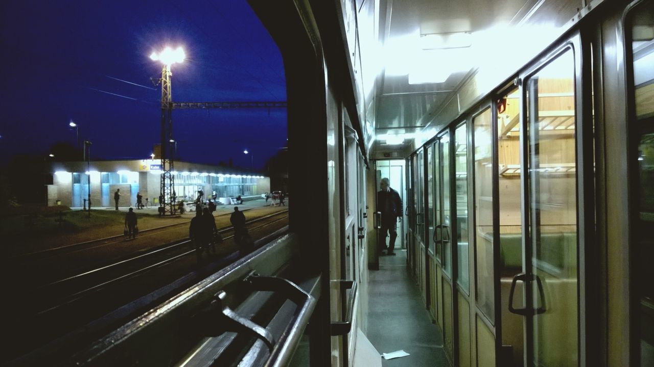 indoors, transportation, lifestyles, illuminated, men, public transportation, travel, person, passenger, mode of transport, leisure activity, window, standing, reflection, journey, glass - material, train - vehicle, railroad station