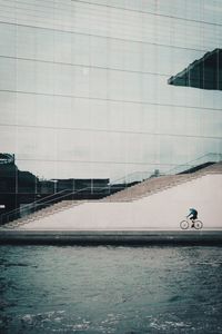 Man on bicycle in city against sky