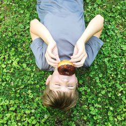 High angle view of boy eating donut while lying down on field at park