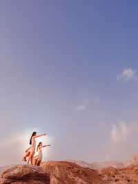 Man standing on rock in desert against sky