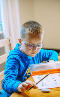 Side view of boy reading book at home