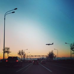 Cars on road against clear sky at sunset