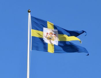 Low angle view of flag against blue sky