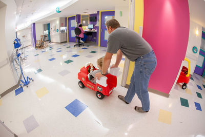 Rear view of people with toy standing on tiled floor