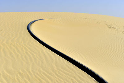 Close-up of sand dunes at beach against clear sky