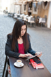 Woman using digital tablet while having coffee at outdoor cafe