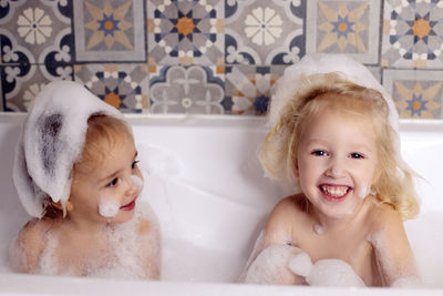 Portrait of cute girls sitting in bathtub