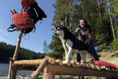 Woman with dog on pier by lake against trees