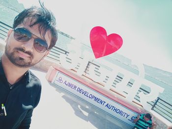 Portrait of young man with heart shape made from sunglasses