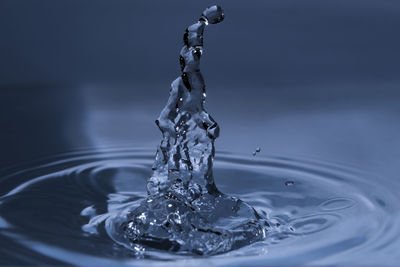 Close-up of splashing water drops causing wavy water surface and water column