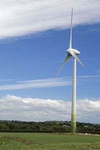 Wind turbines on field against sky