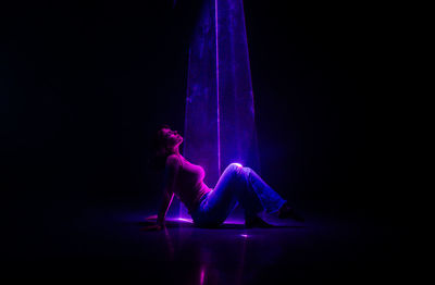 Low angle view of woman standing against black background