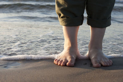 Low section of man standing on beach