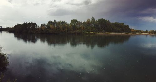 Scenic view of lake by trees against sky