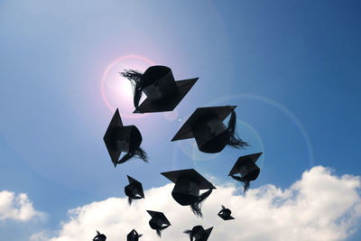 Low angle view of mortarboards against sky