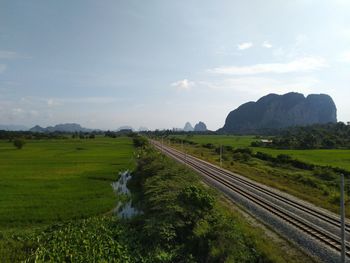 Scenic view of railroad tracks on field against sky