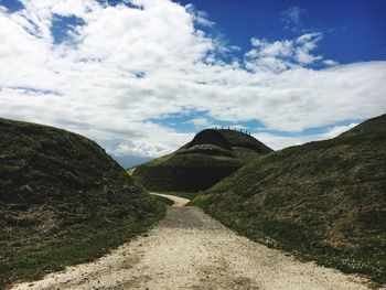 Empty footpath by mountains against sky