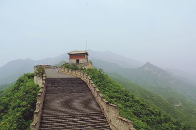 Building and steps at great wall of china against sky in foggy weather