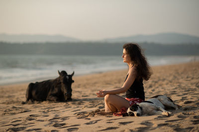 Side view of a woman meditating on beach