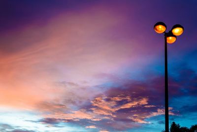 Low angle view of illuminated street light against cloudy sky