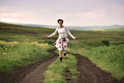 Full length of woman running on field against sky