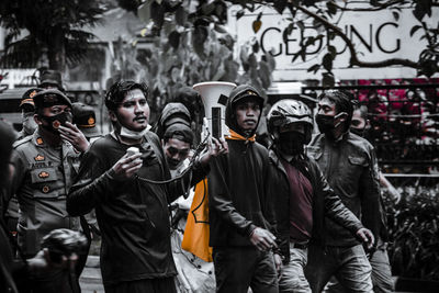 Rear view of people standing against graffiti wall