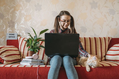 Home office, work space, work from home concept. young woman with laptop and cat working 