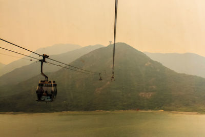 Overhead cable car over mountains against sky