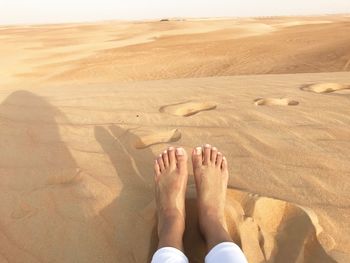 Low section of woman lying on sand