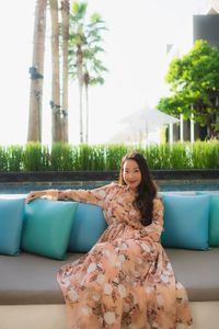 Portrait of woman sitting on armchair against trees