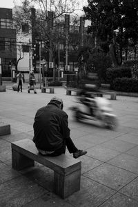 Rear view of man sitting on street in city