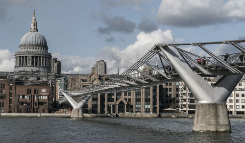 Bridge over river against sky in city