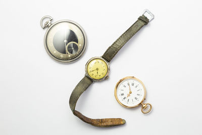 Directly above shot of pocket watches and wristwatch against white background