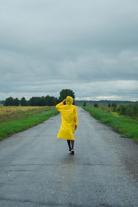 Rear view of woman on yellow road against sky