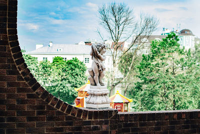 Statue by trees and building against sky