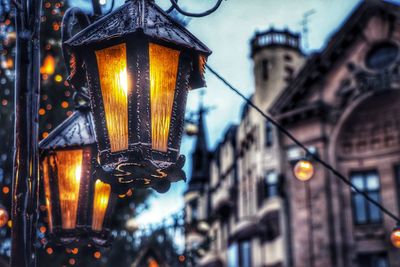 Low angle view of illuminated lanterns hanging on street by buildings