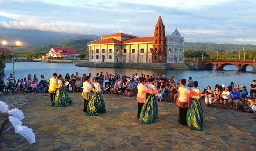 Group of people dancing by river in city