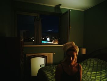 Young woman sitting in illuminated room